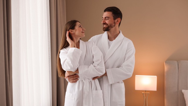 Pareja disfrutando de una habitación de hotel impoluta, con batas blancas.