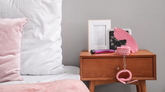 Habitación de motel erótico con juguetes sexuales en la mesa de noche