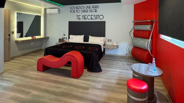 Habitación de motel con motivos rojos y diferentes aparatos para tener relaciones sexuales.