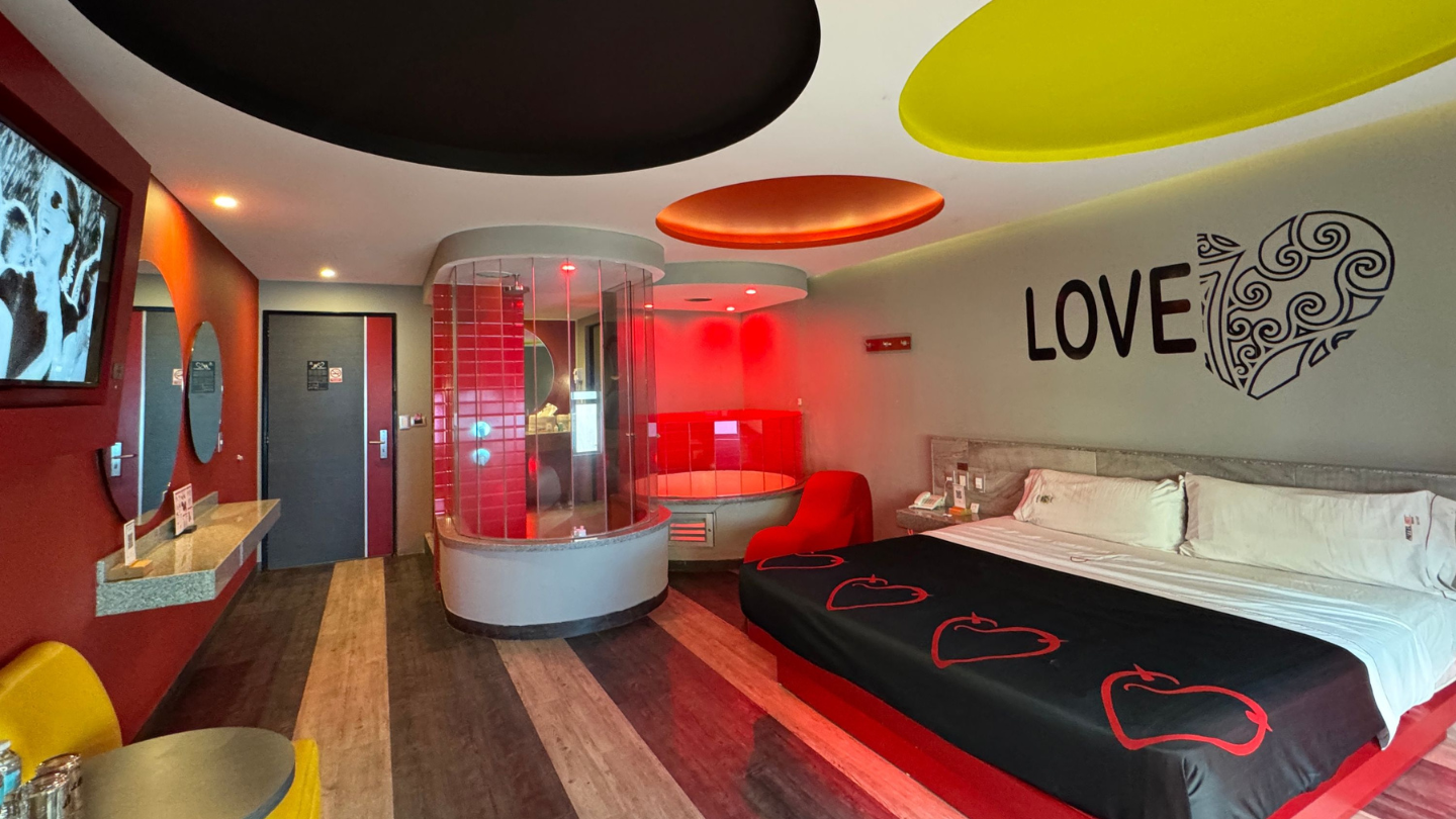 Habitación de motel con tonos rojos y una ducha en el centro