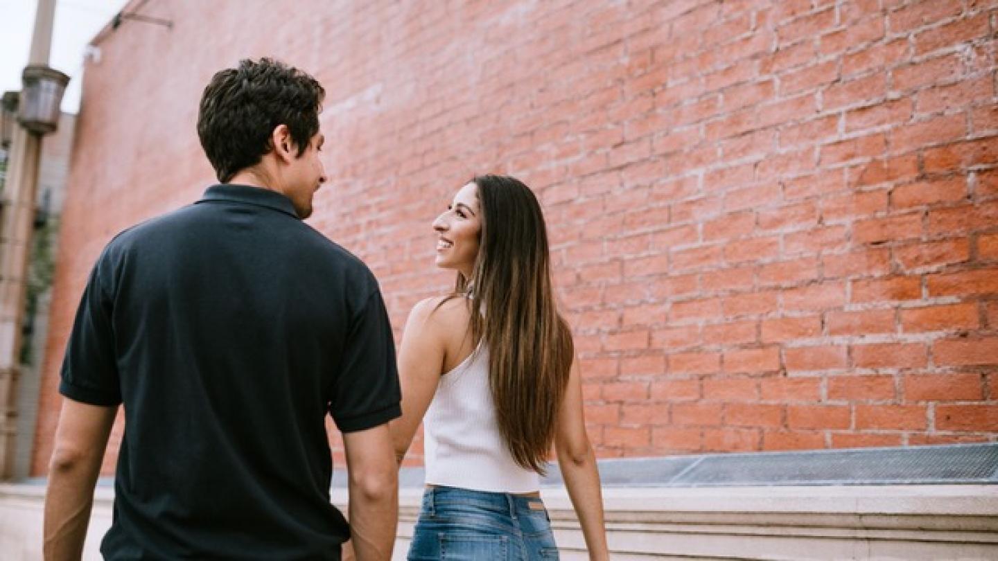 Pareja de novios jóvenes que van por la calle y se plantean si es malo ir a un motel