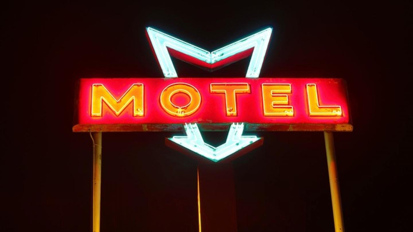 Anuncio de motel luminoso con letras rojas, en la noche.